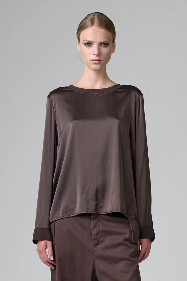 Woman wearing a brown satin top and pants on a gray background