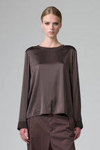 Woman wearing a brown satin top and pants on a gray background