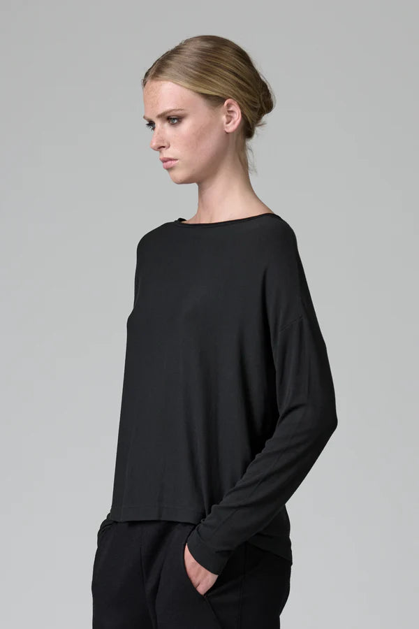 Woman wearing a black long-sleeve top against a gray background