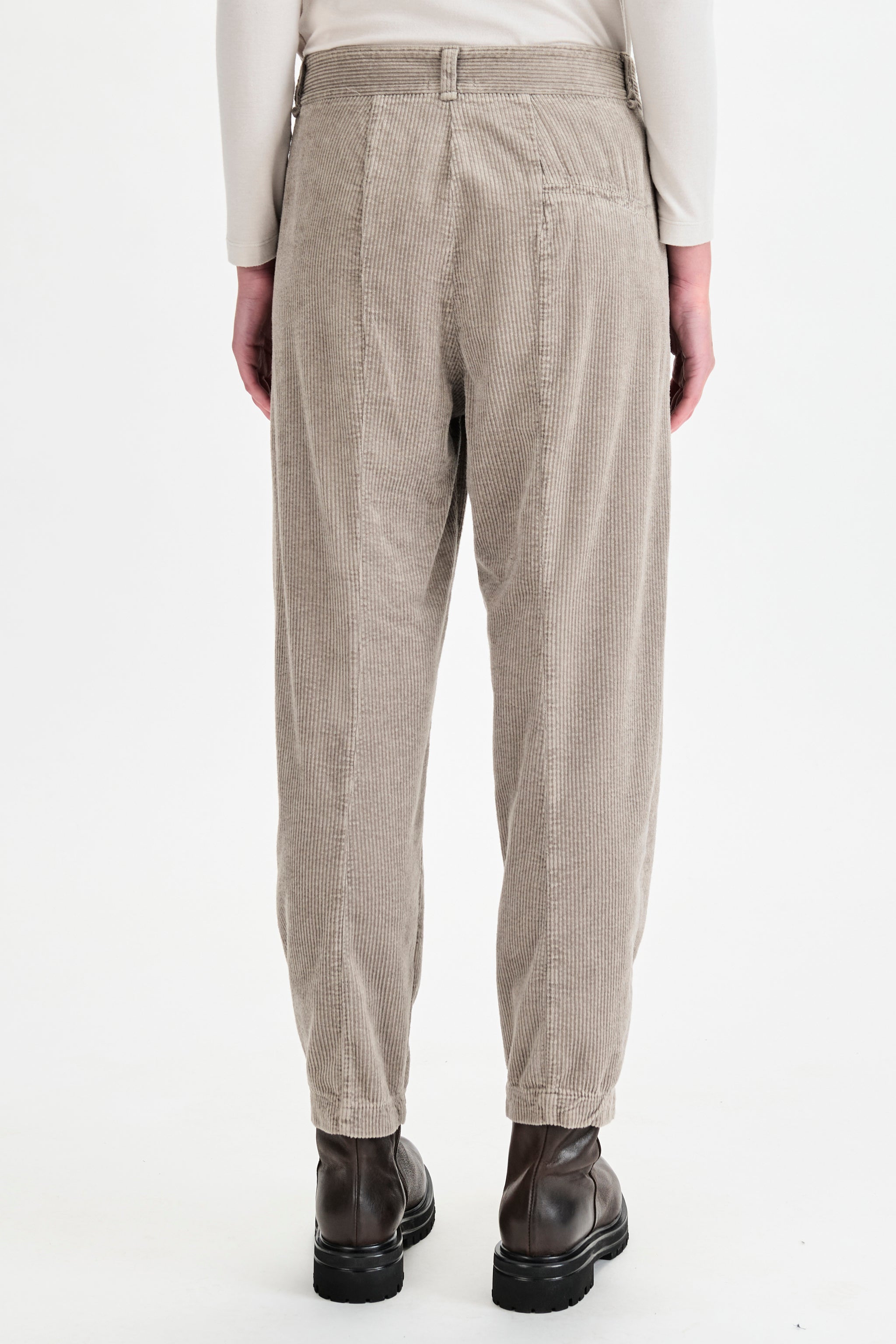Beige corduroy pants worn by a person on a white background