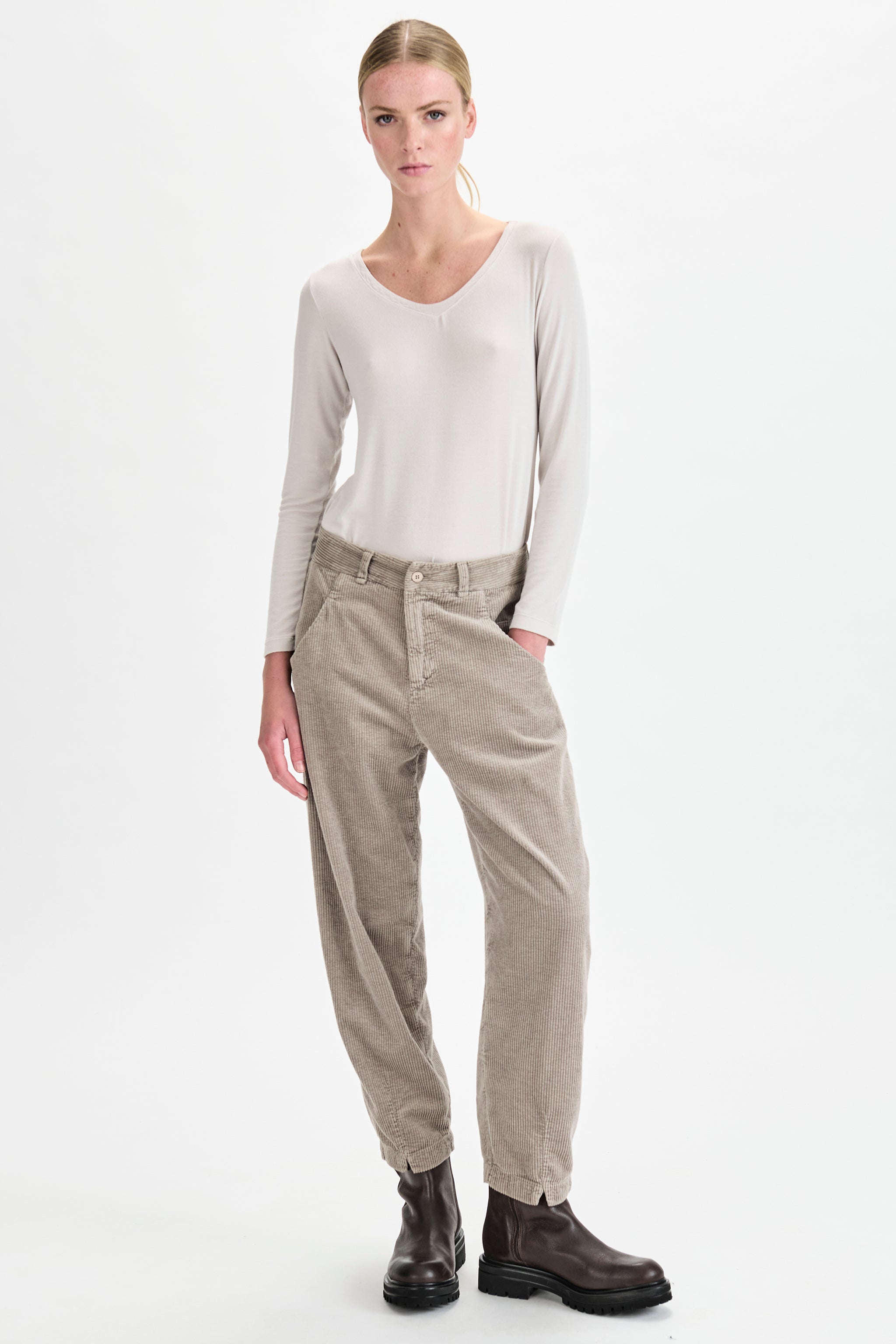 Woman wearing a white top and beige pants on a white background