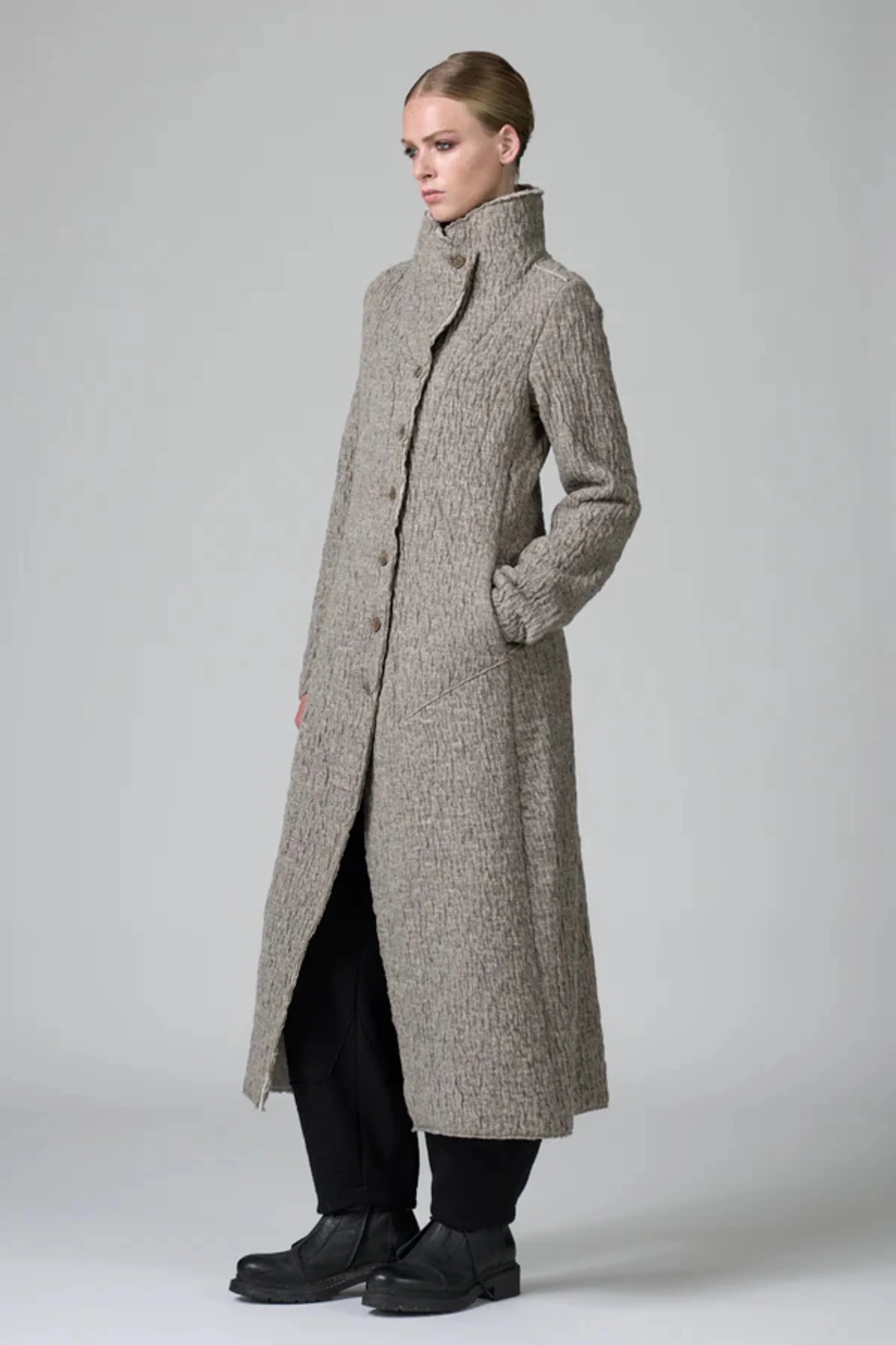 Woman wearing a long gray coat on a white background
