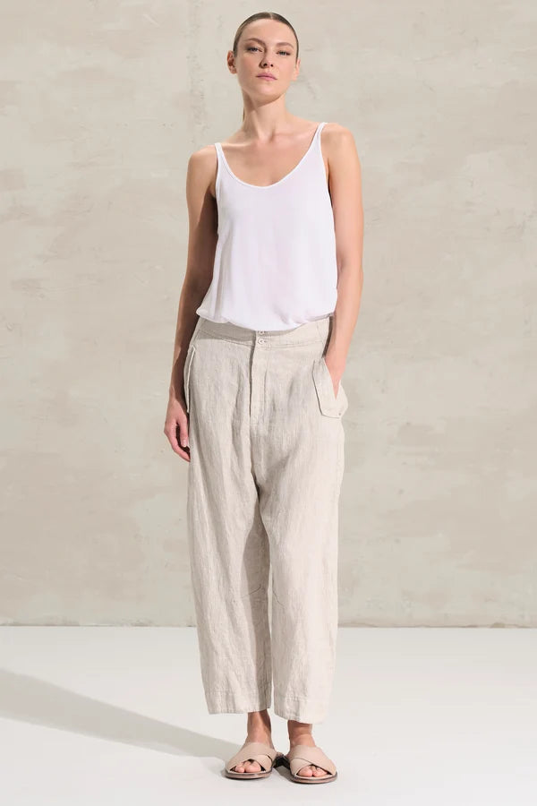 women wearing Transit pants with a soft fit, slightly arched leg and pockets on the side with flaps on the front and welt on the back. Garment made of linen and cupro fabric with micro pattern.
