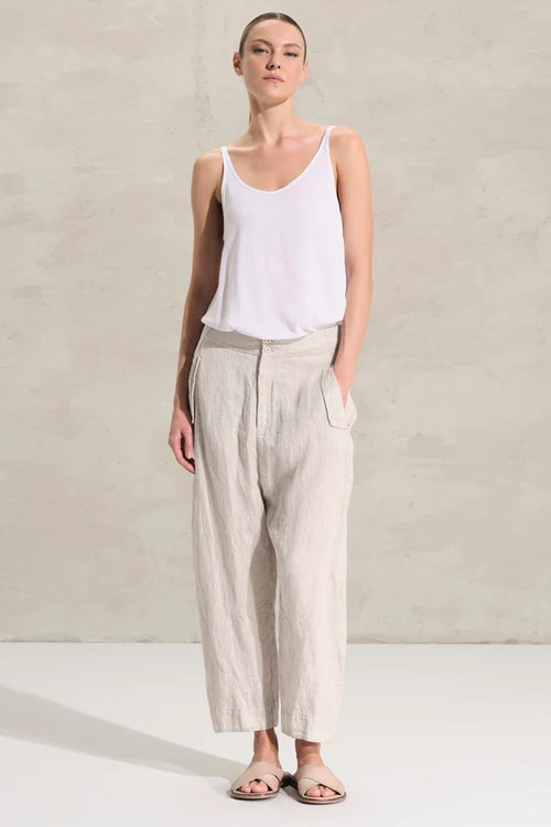 women wearing Transit pants with a soft fit, slightly arched leg and pockets on the side with flaps on the front and welt on the back. Garment made of linen and cupro fabric with micro pattern.