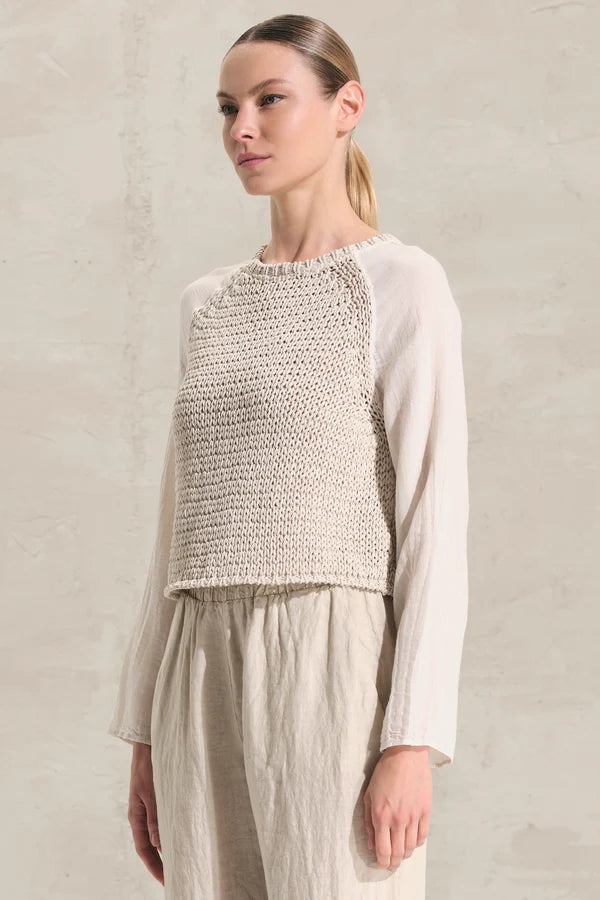 Woman wearing a textured top and pants against a neutral background