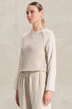 Woman wearing a textured top and pants against a neutral background