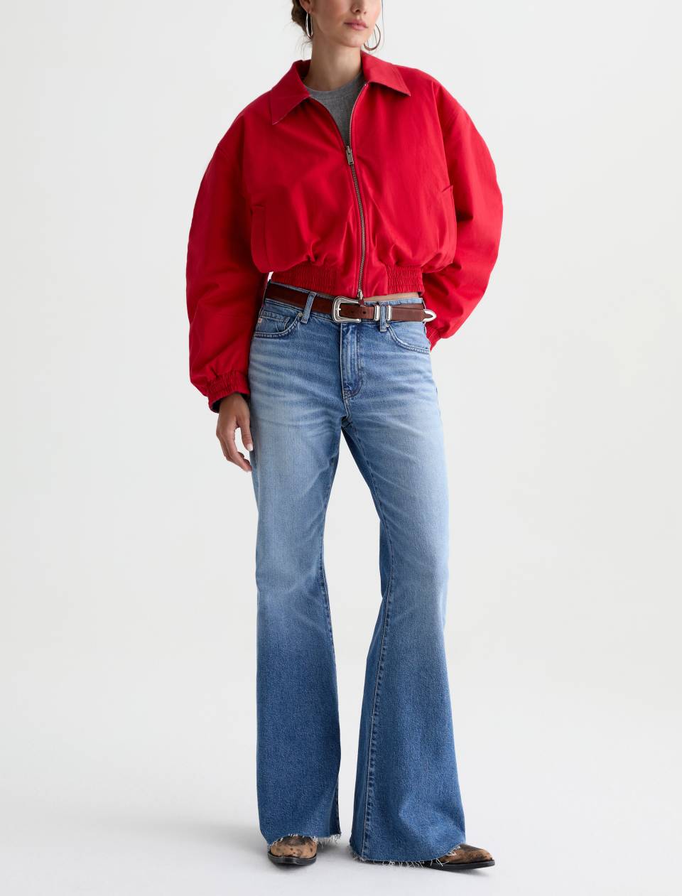 Person wearing a red jacket and blue jeans on a white background
