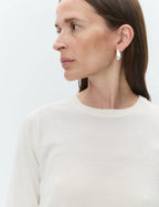 Woman wearing silver hoop earrings on a plain background