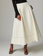 White skirt worn by a person on a plain background