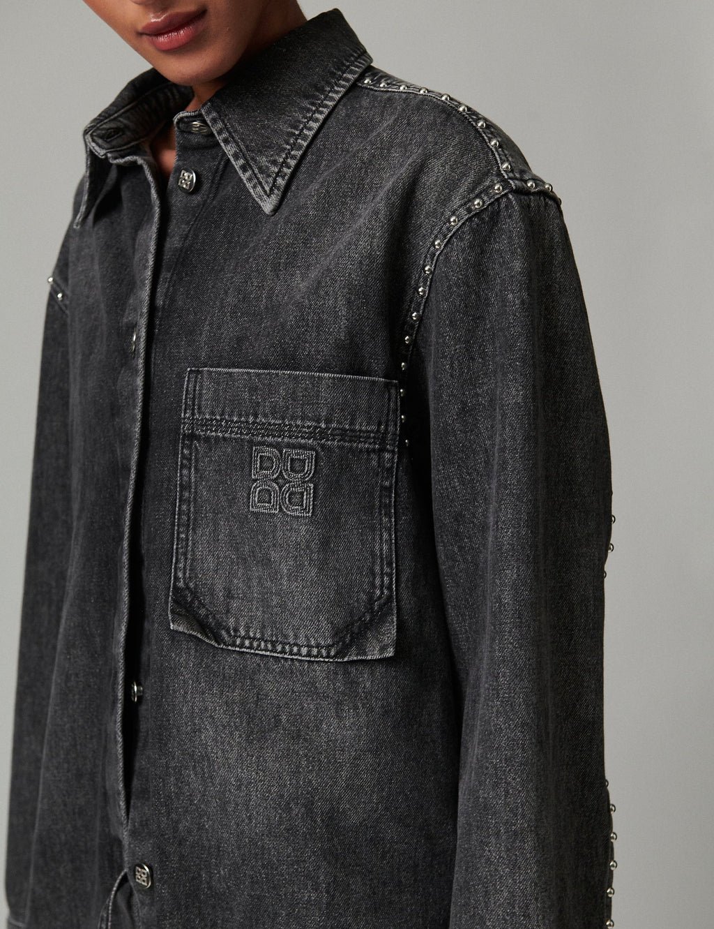 Black denim shirt with studded details on a gray background