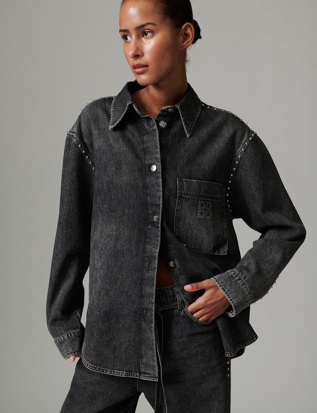 Person wearing a dark denim jacket on a gray background