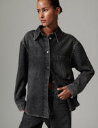 Person wearing a dark denim jacket on a gray background