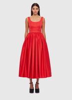 A woman standing wearing a red, premium fitted midi dress with a scoop neckline, fitted bodice, and gathered A-line skirt.