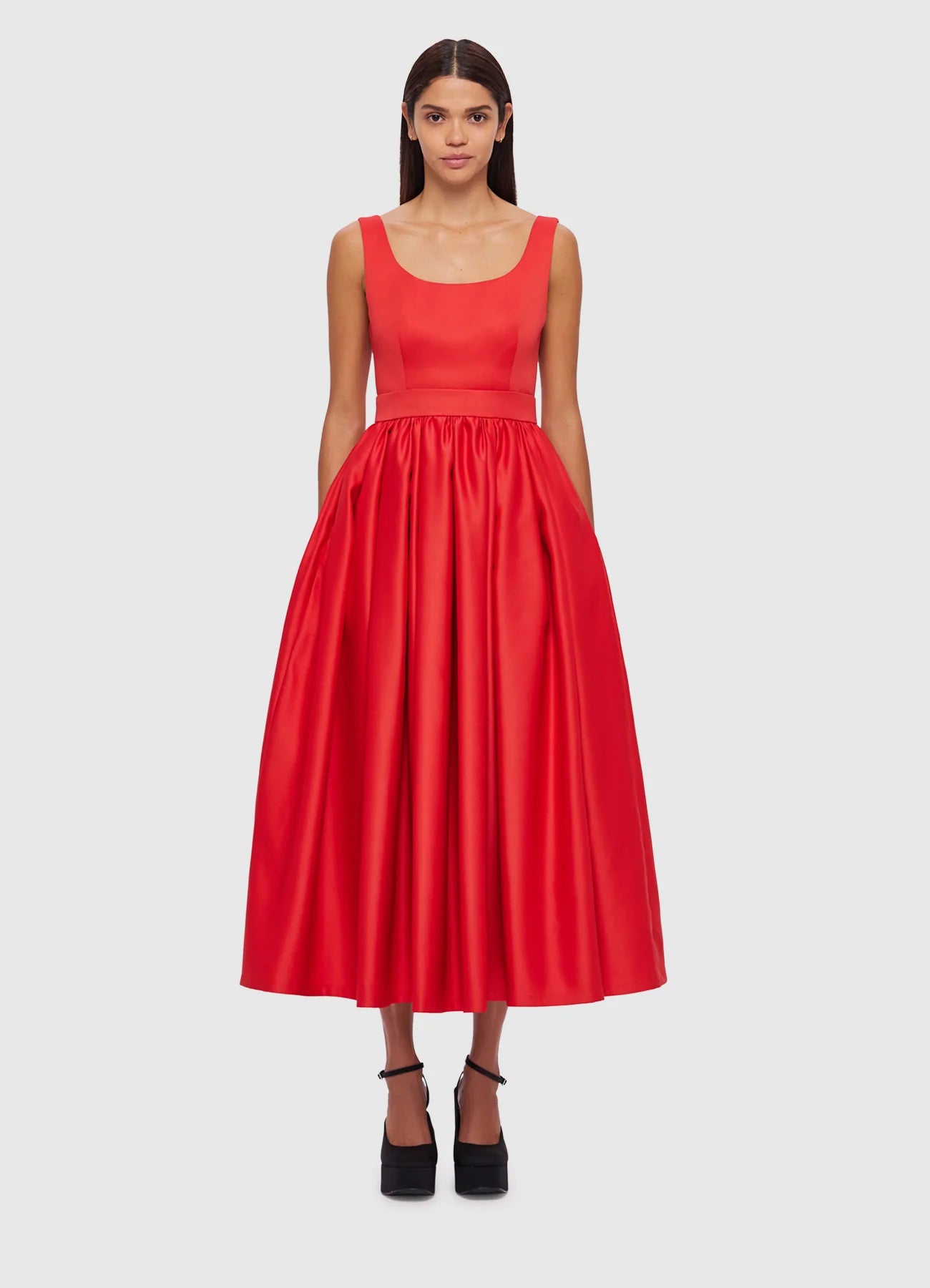 A woman standing wearing a red, premium fitted midi dress with a scoop neckline, fitted bodice, and gathered A-line skirt.