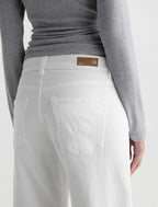 Person wearing light gray pants with a brand label on a white background