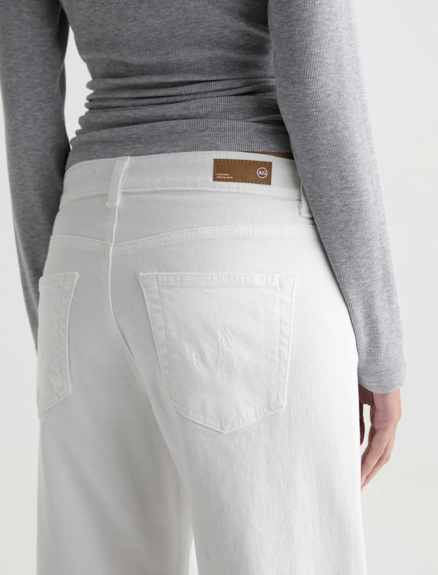 Person wearing light gray pants with a brand label on a white background