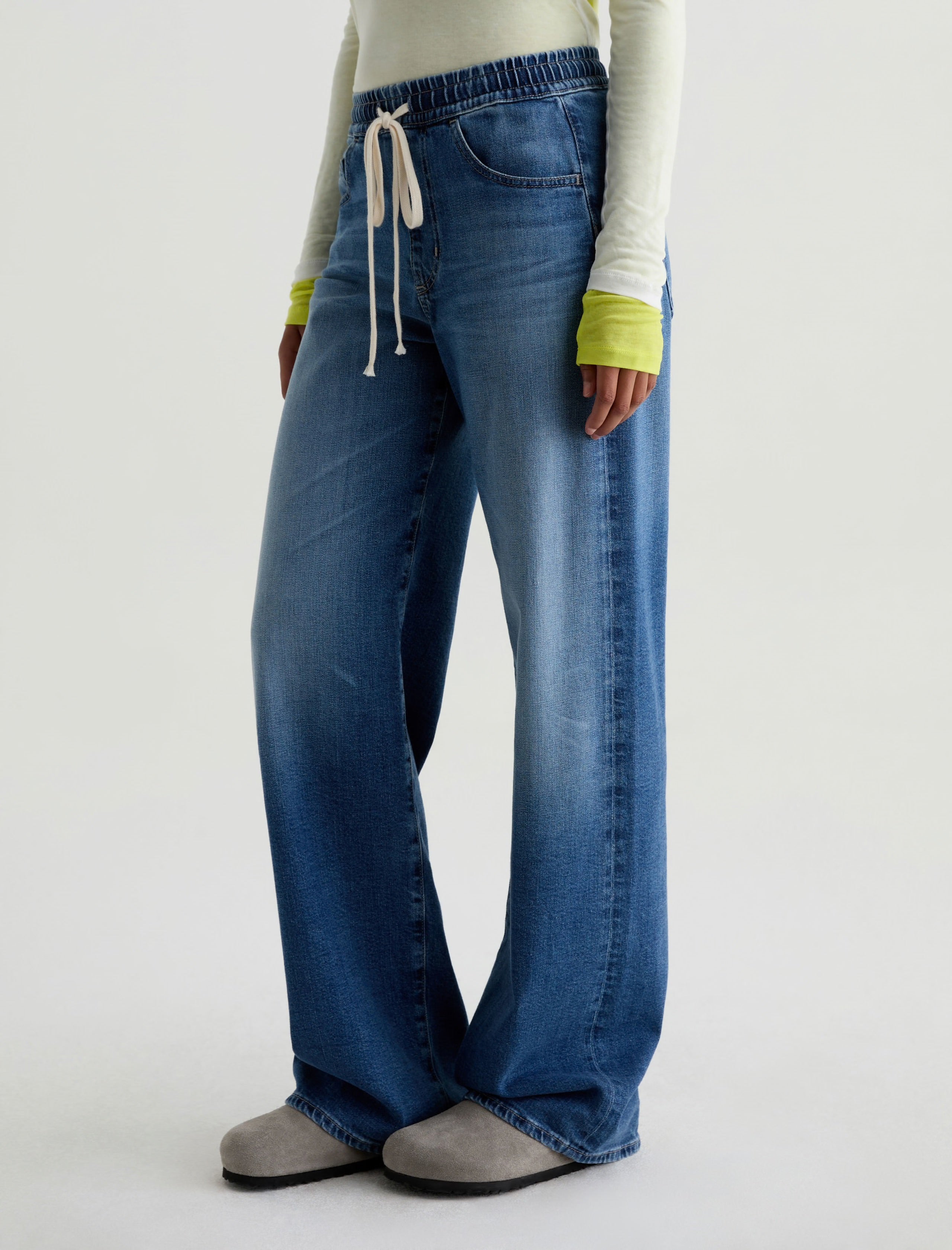 Person wearing blue flared jeans on a white background