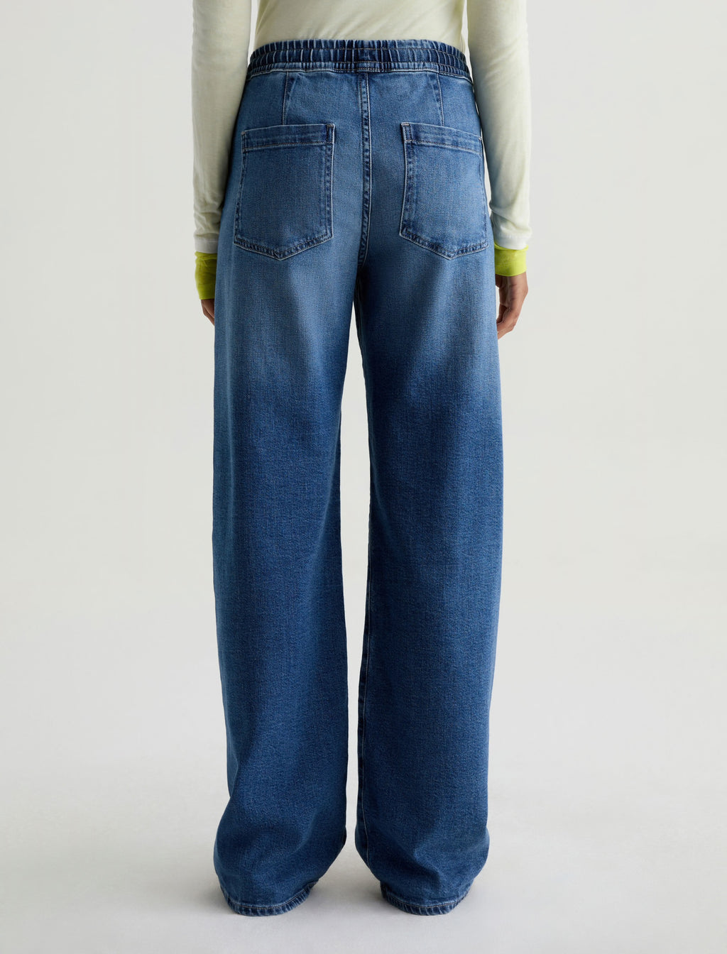 Person wearing blue jeans on a plain background