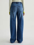 Person wearing blue jeans on a plain background