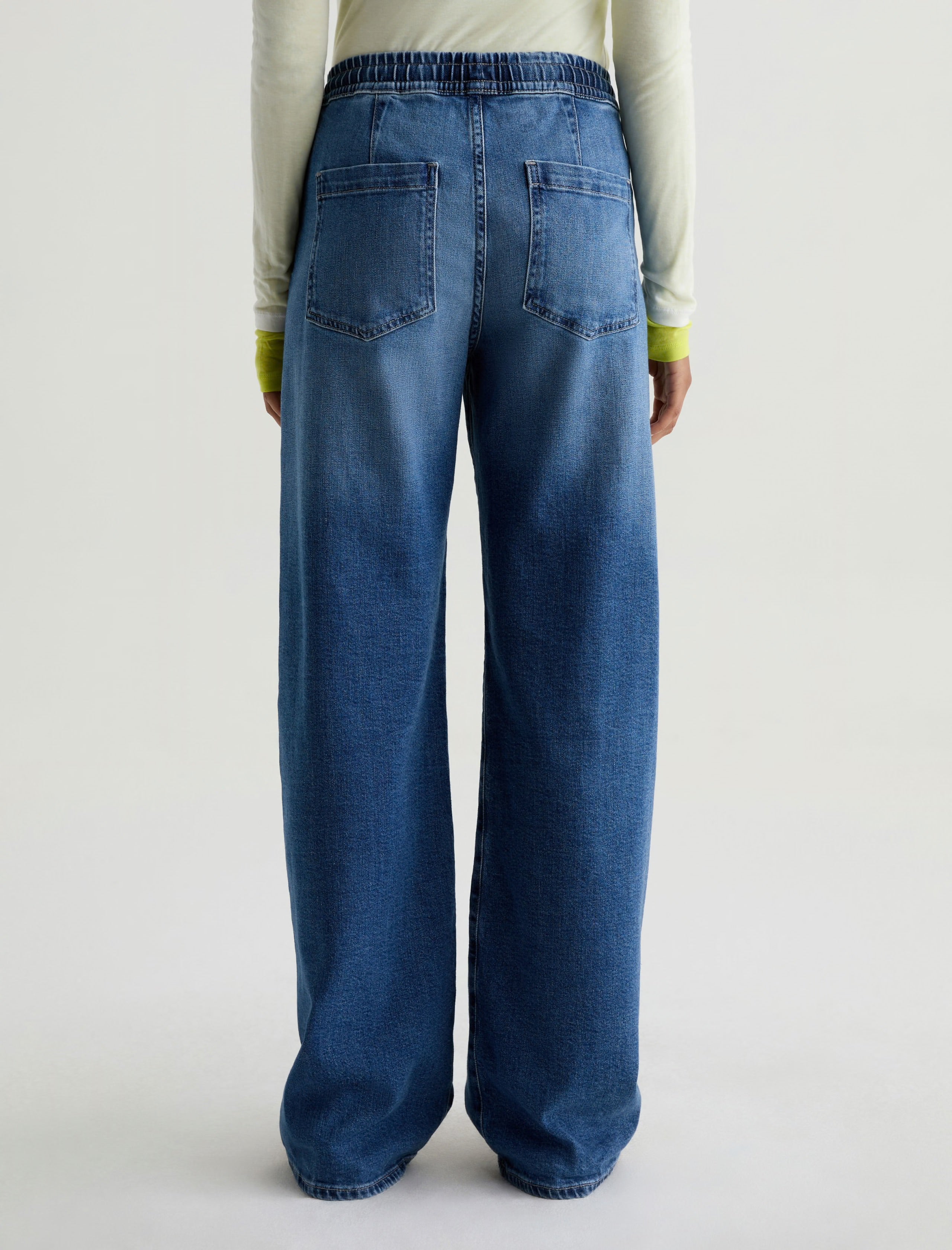 Person wearing blue jeans on a plain background