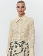 Woman wearing a Day Birger et Mikkelsen beige lace blouse with black floral embroidery on a white background