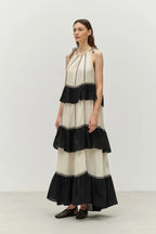 Woman wearing a black and white dress with ruffled layers on a plain background