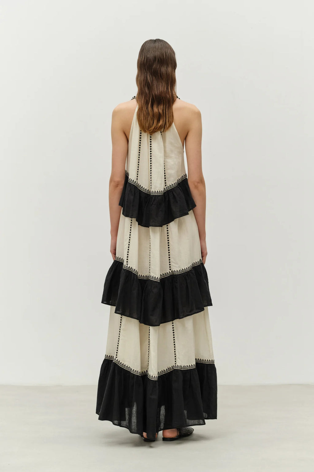 Woman wearing a black and white dress with ruffled layers on a plain background