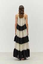 Woman wearing a black and white dress with ruffled layers on a plain background