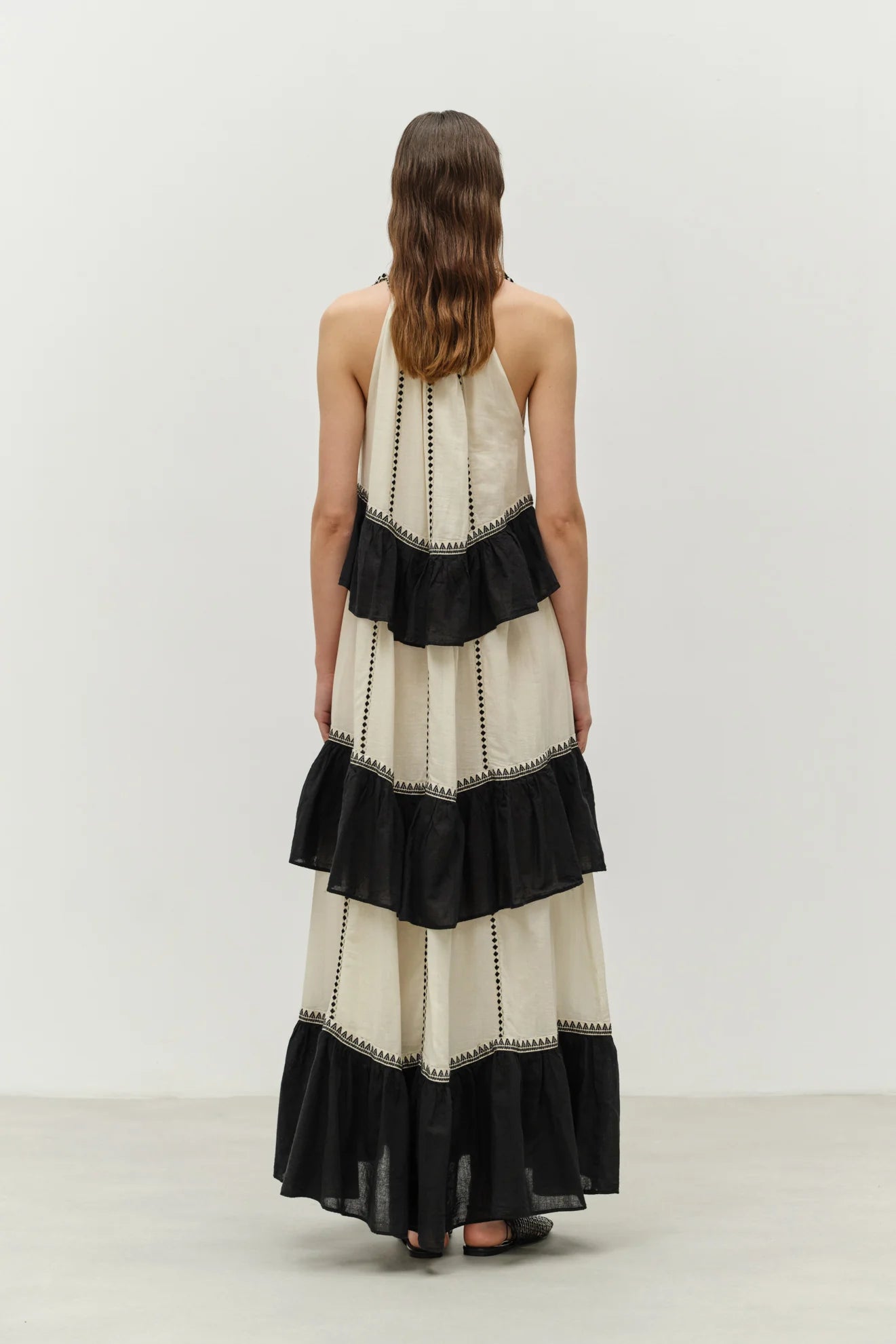 Woman wearing a black and white dress with ruffled layers on a plain background