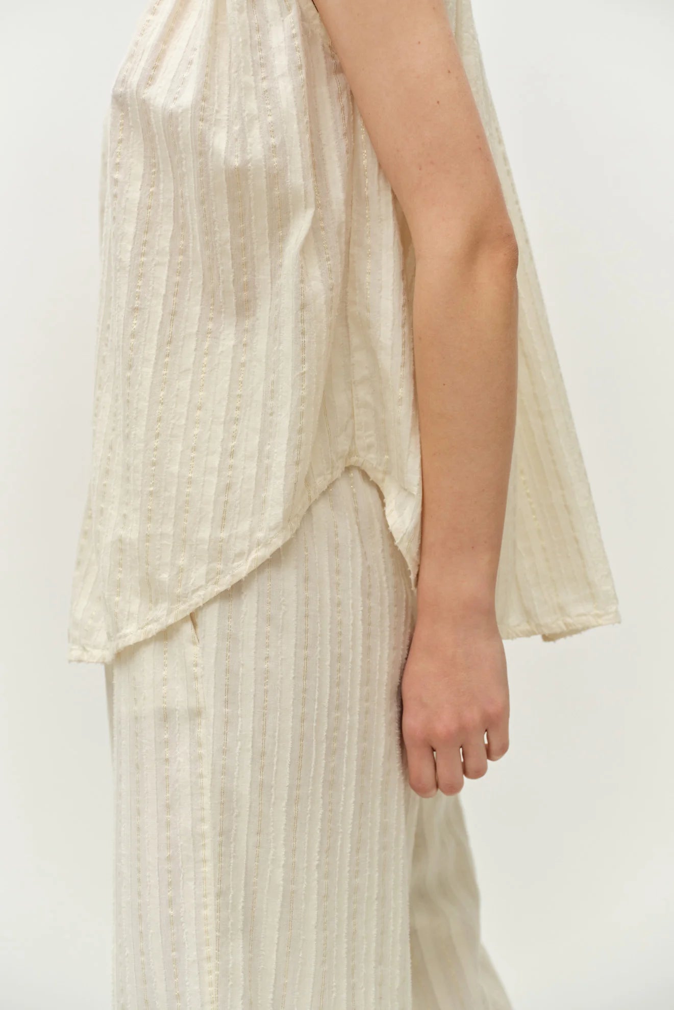 Person wearing a light-colored dress with a plain background