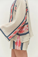 Beige cardigan with red and blue striped trim over a matching dress on a white background