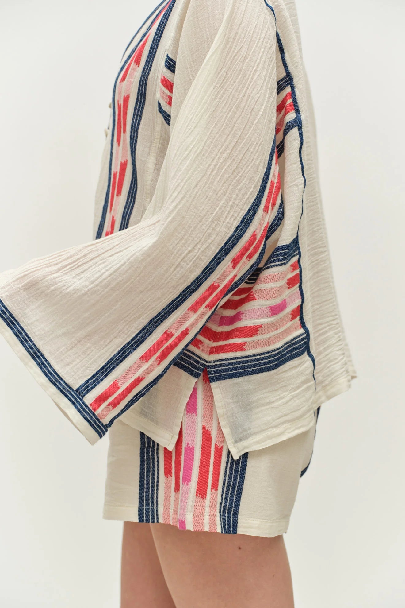 Beige cardigan with red and blue striped trim over a matching dress on a white background