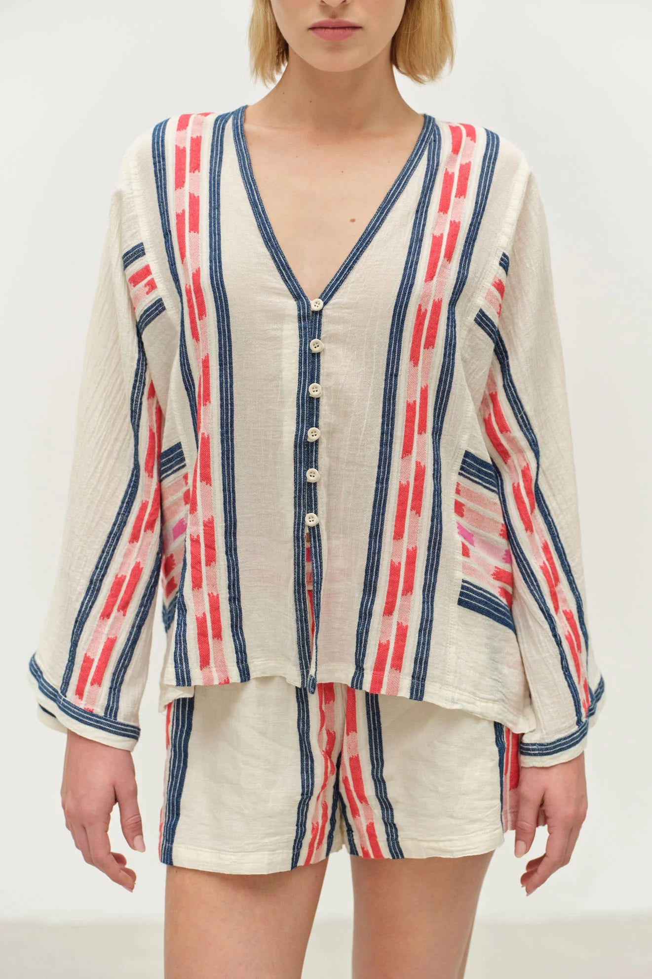 Person wearing a striped cardigan and shorts set on a plain background