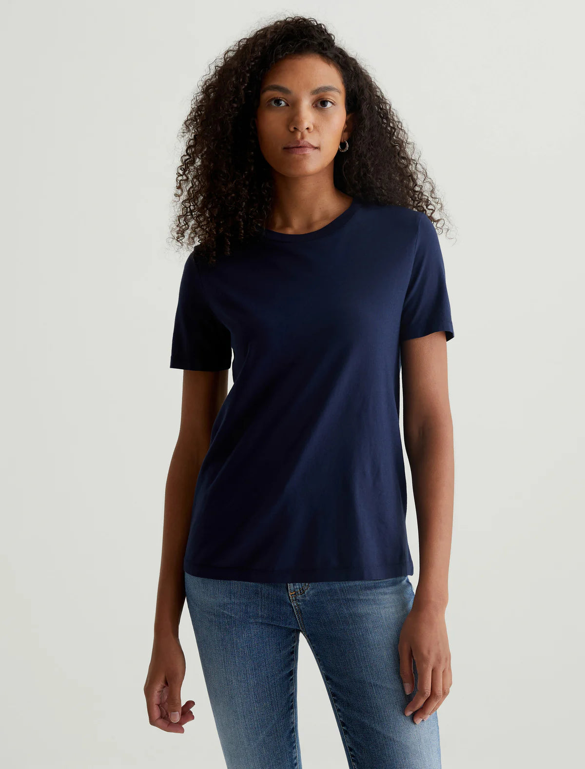A person wearing a deep navy crew neck t-shirt paired with jeans.