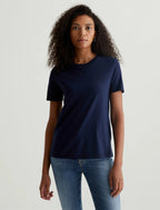 A person wearing a deep navy crew neck t-shirt paired with jeans.