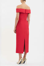 A woman shown from the back wearing a bright red off-the-shoulder midi dress with a fitted bodice and front slit, paired with metallic gold high heels against a plain white studio background.