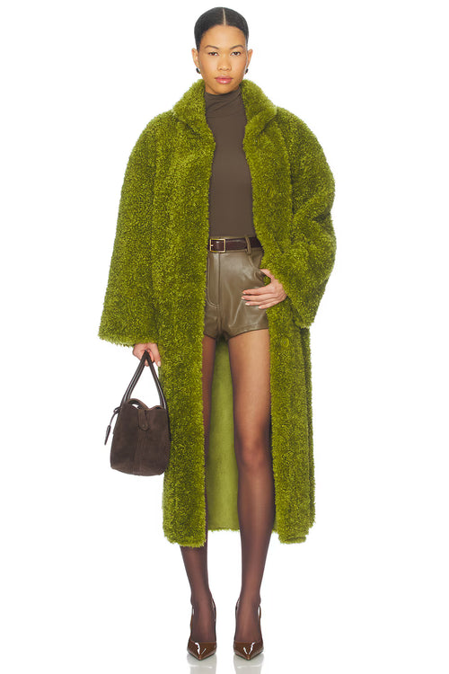 Woman wearing a green fur coat with a plain background