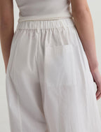White pants worn by a person on a plain background