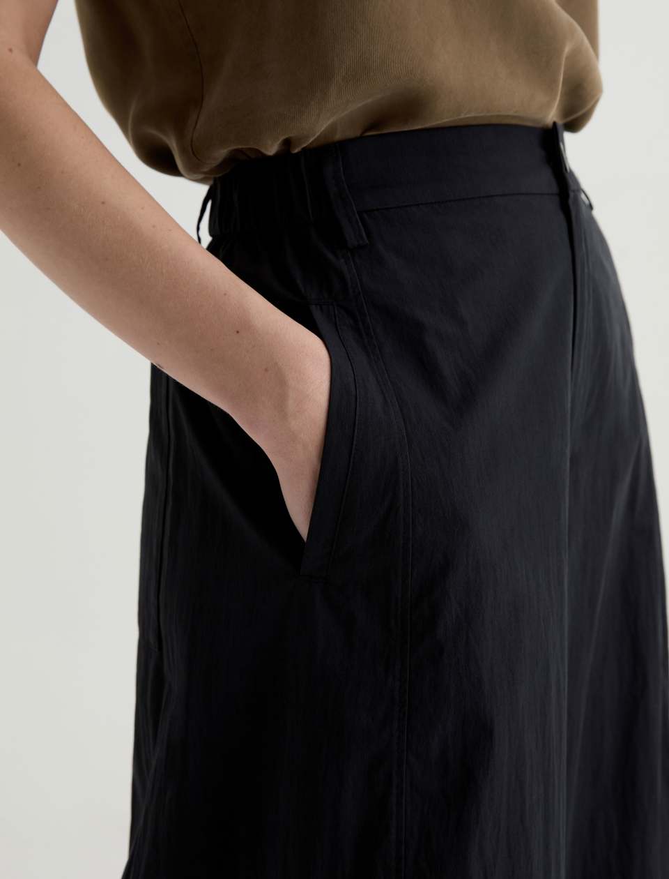 Person wearing a brown top and black pants on a plain background