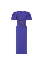 The Rebecca Vallance Evolet Puff Sleeve Midi Dress is captivating in a vibrant ultra marine blue, adorned with intricate floral embellishments. Tailored from bonded crepe, its crew neckline and voluminous short puff sleeves create a refined and elegant shape, complemented by a fitted bodice that flatters the figure. The pencil midi skirt creates an elegant silhouette, detailed with a back split for ease of movement. Secured with an invisible zip fastening at the back and lining for comfort, this dress is a 