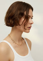 Woman wearing a delicate necklace against a plain background