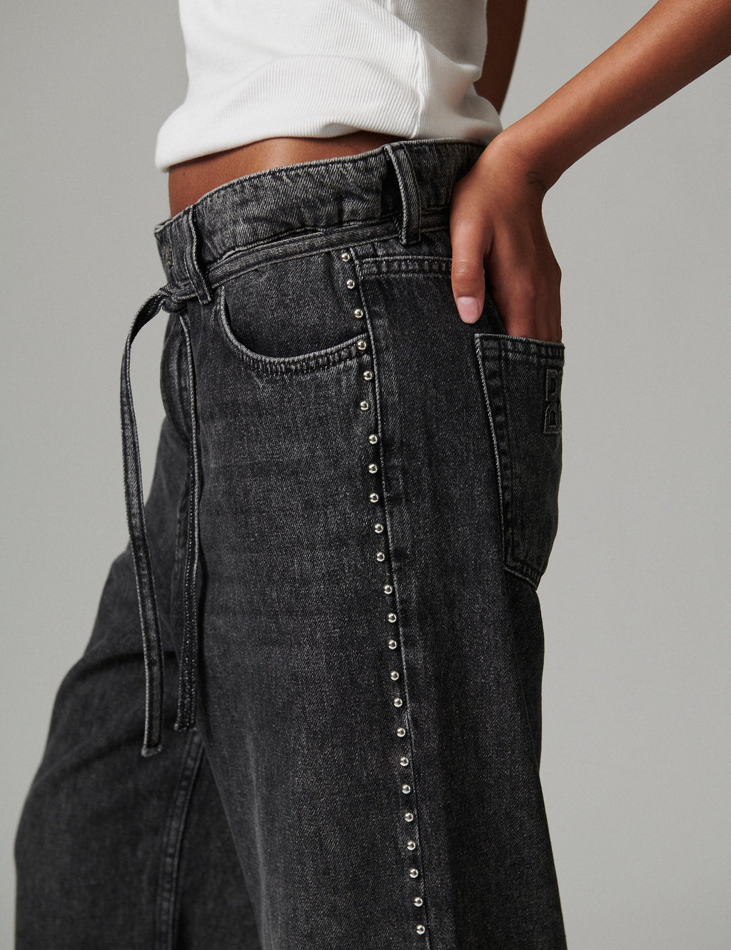 Black jeans with silver studs on a gray background