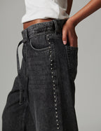 Black jeans with silver studs on a gray background