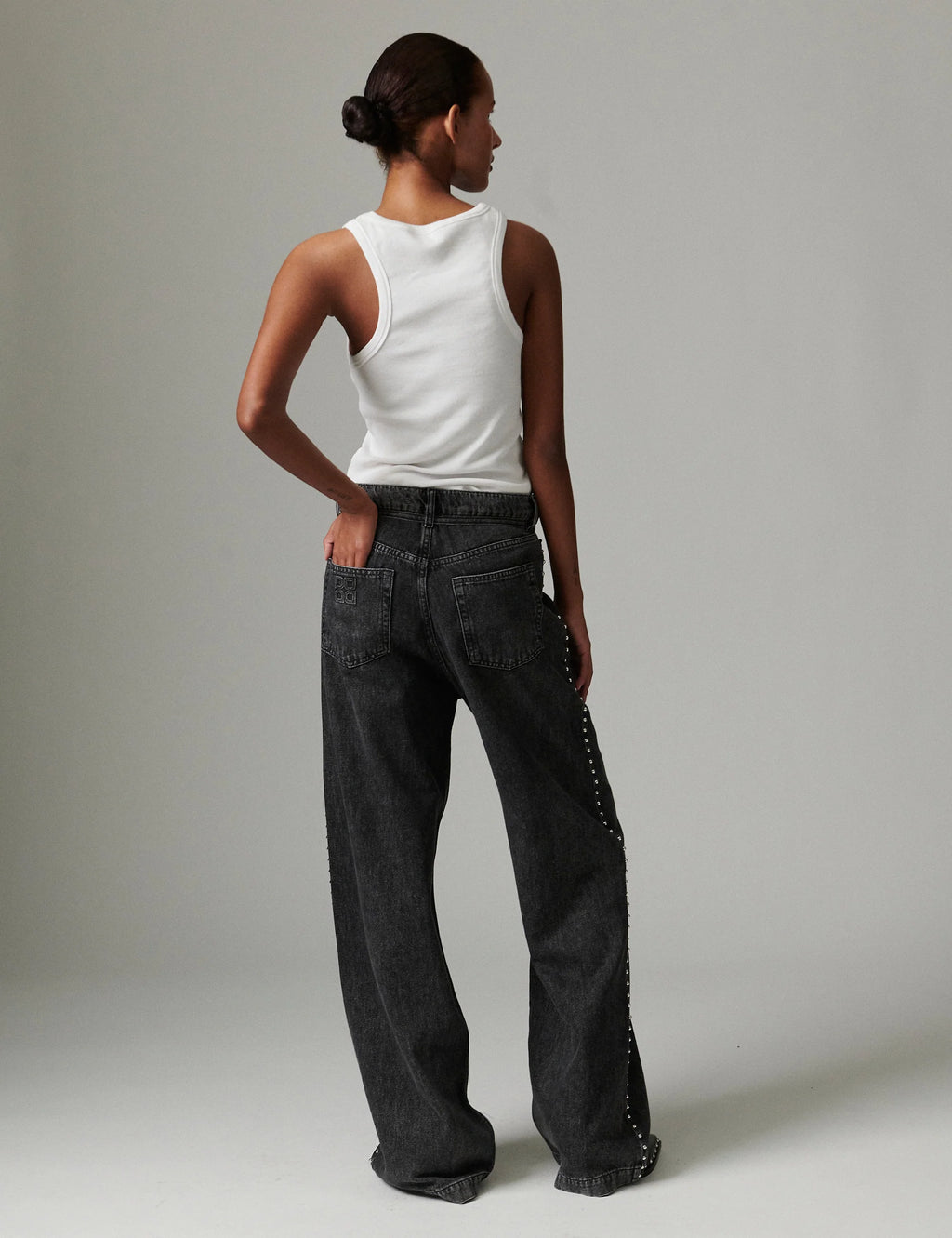 Person wearing a white sleeveless top and black wide-leg pants against a plain background
