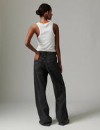 Person wearing a white sleeveless top and black wide-leg pants against a plain background