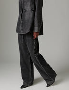 Person wearing a dark gray jacket and wide-leg pants on a plain background