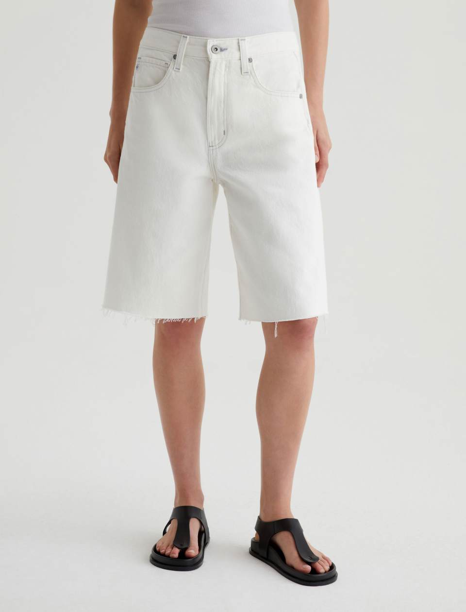 Person wearing white denim shorts on a plain background