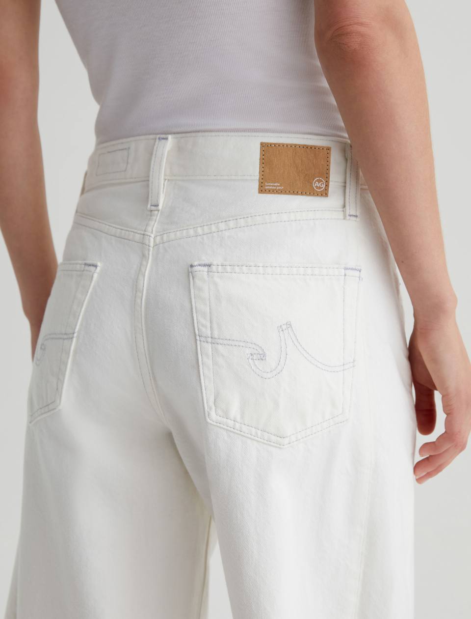 White jeans with a brand label on a plain background