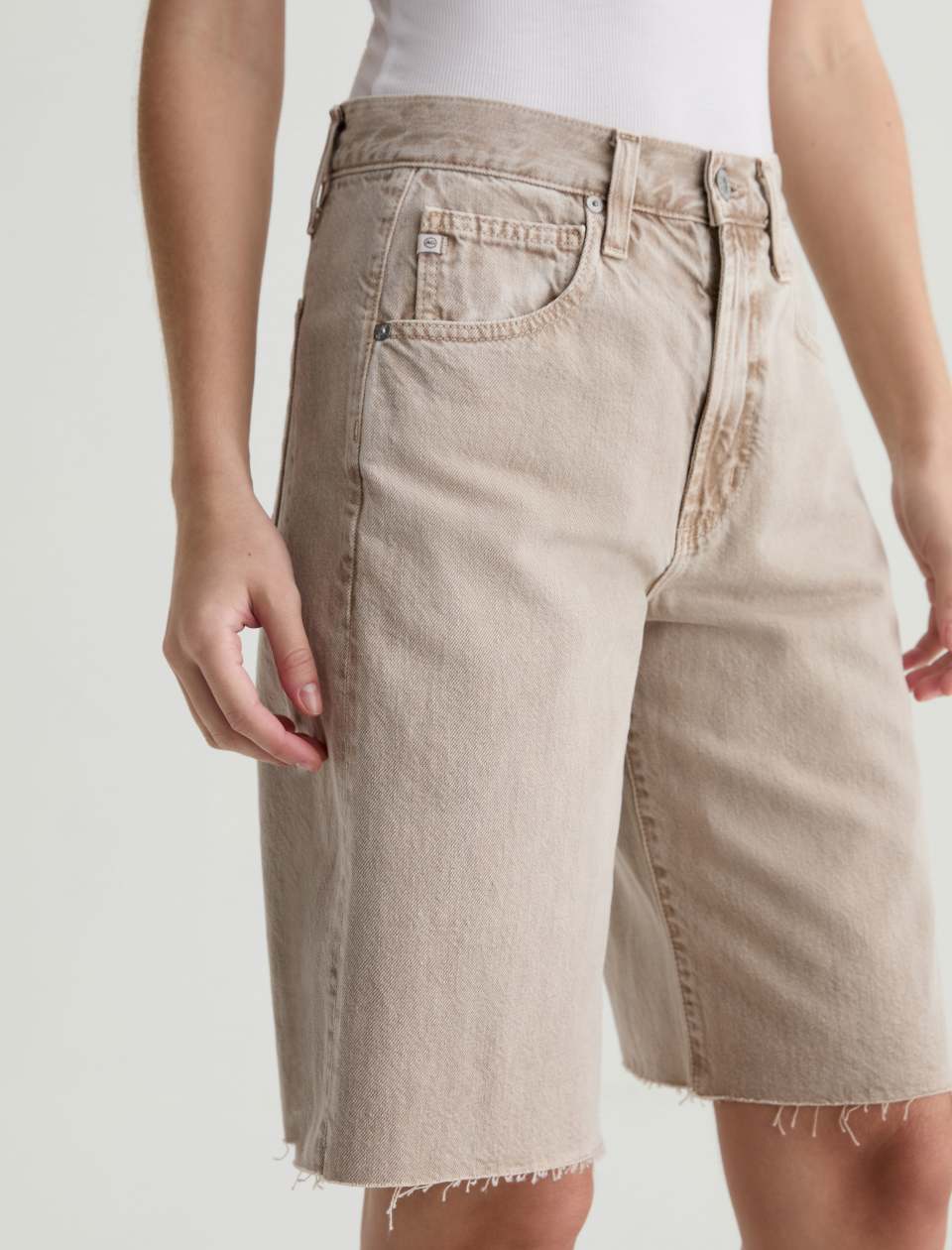 Beige denim shorts worn by a person on a plain background