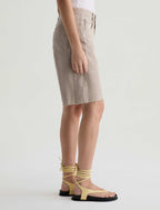 Person wearing a beige skirt and yellow strappy sandals on a white background